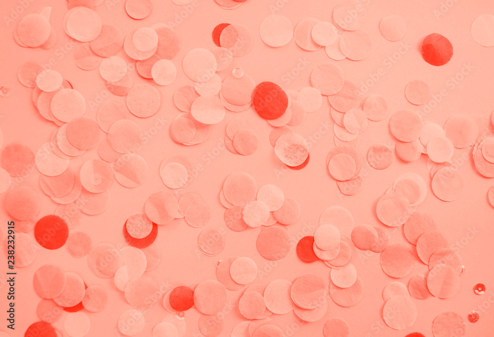 Flat lay of living coral color confetti and sparkles on pink background. Color of the year 2019 concept.