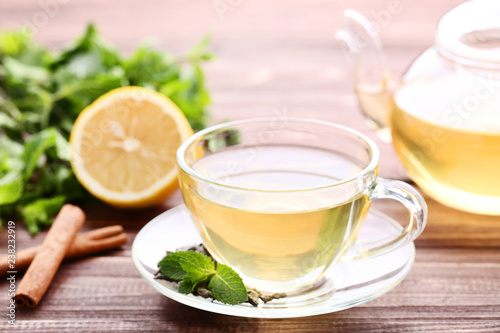 Cup of tea with lemon, mint leafs and cinnamon sticks on wooden table