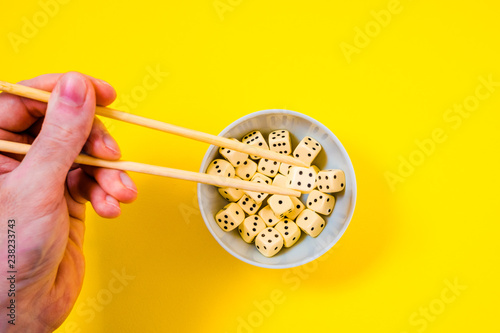 dice in white bowl with chopsticks on yellow background