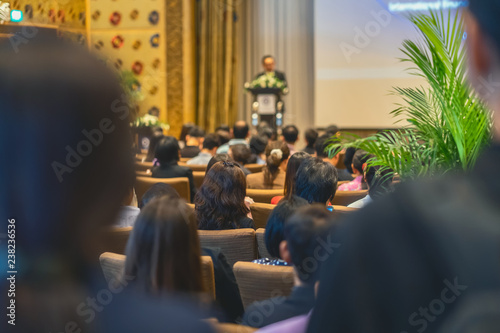 Back side of audience listening the Speaker with podium on the stage in the conference hall, business and education concept photo