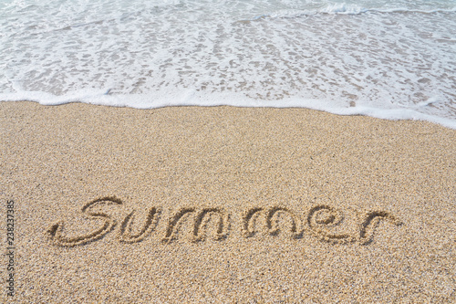 Summer inscription on a tropical sandy beach with blue sea, waves and foam on a background.