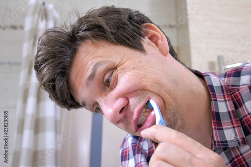 Crazy Young man cleans his teeth in the bathroom.