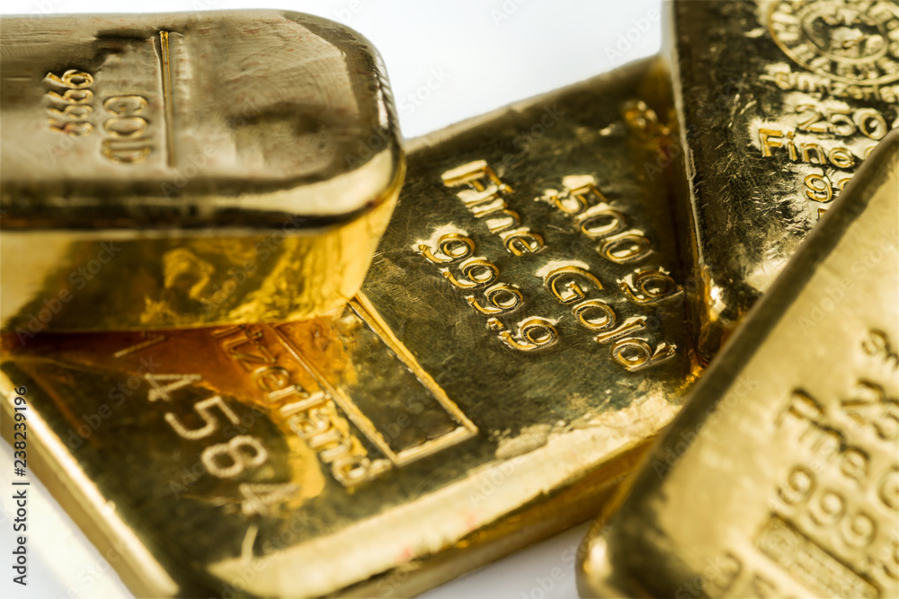 Several cast gold bars of different weights isolated on white background. Selective focus. Several cast gold bars of different weights isolated on white background. Selective focus.