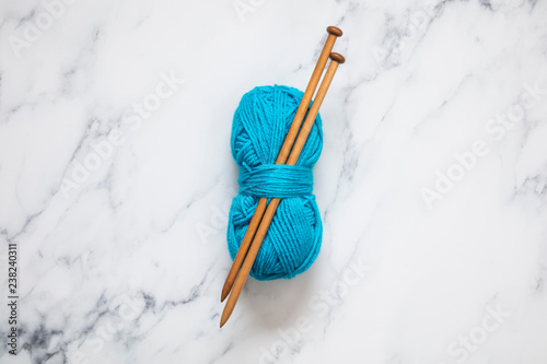 A ball of turquoise blue wool with wooden knitting needles