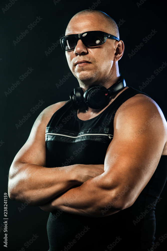 Man posing in sunglasses and headphones. Sport and fashion concept isolated on black background.