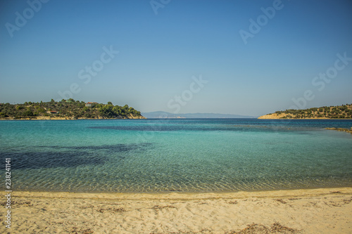 Aegean sand sea shore line Greece beach in summer clear hot weather time, colorful environment landscape of vivid blue water and opposite islands  © Артём Князь