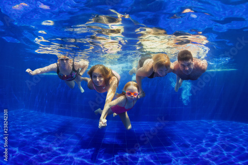 Happy family in swimming pool. Smiling mother, children and grandparents swim, dive in pool with fun - jump deep down underwater. Healthy lifestyle, people water sport activity on holidays with kids