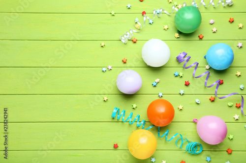 Colorful balloons with paper stars on green wooden table