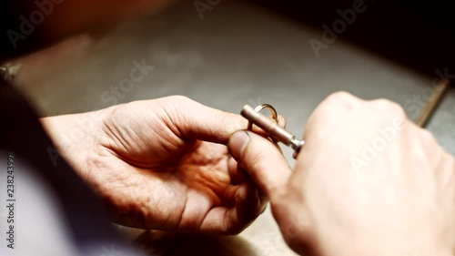 Jeweler polishing gold ring in workshop with professional jewelry tools. Goldsmith working, forming making decoration on silver ring in workplace. Craft jewellery making. Jewelry maker hands close-up.