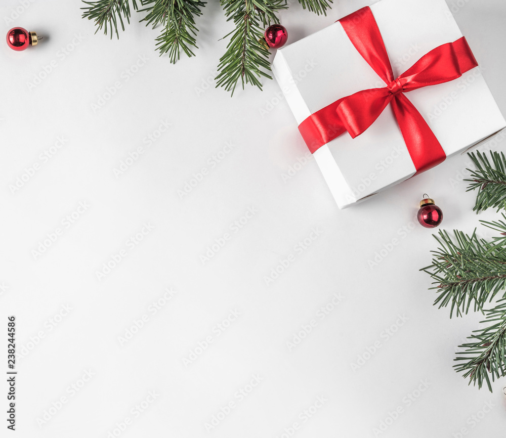 Creative frame made of Christmas fir branches on white paper background with red decoration, pine cones, gift boxes. Xmas and New Year theme. Flat lay, top view Creative frame made of Christmas fir branches on white paper background with red decoration, pine cones, gift boxes. Xmas and New Year theme. Flat lay, top view