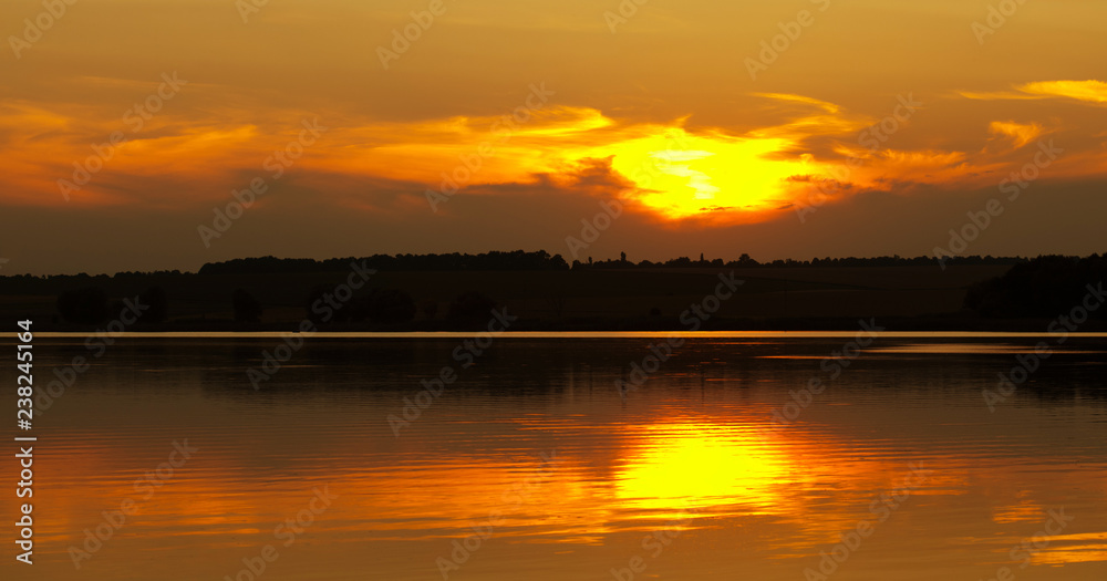 Panorama sunset on the lake. Beautiful colors evening nature landscape. forest silhouette and the rays of the sunlight.