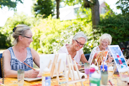 Happy elderly women attending an outdoor art class.