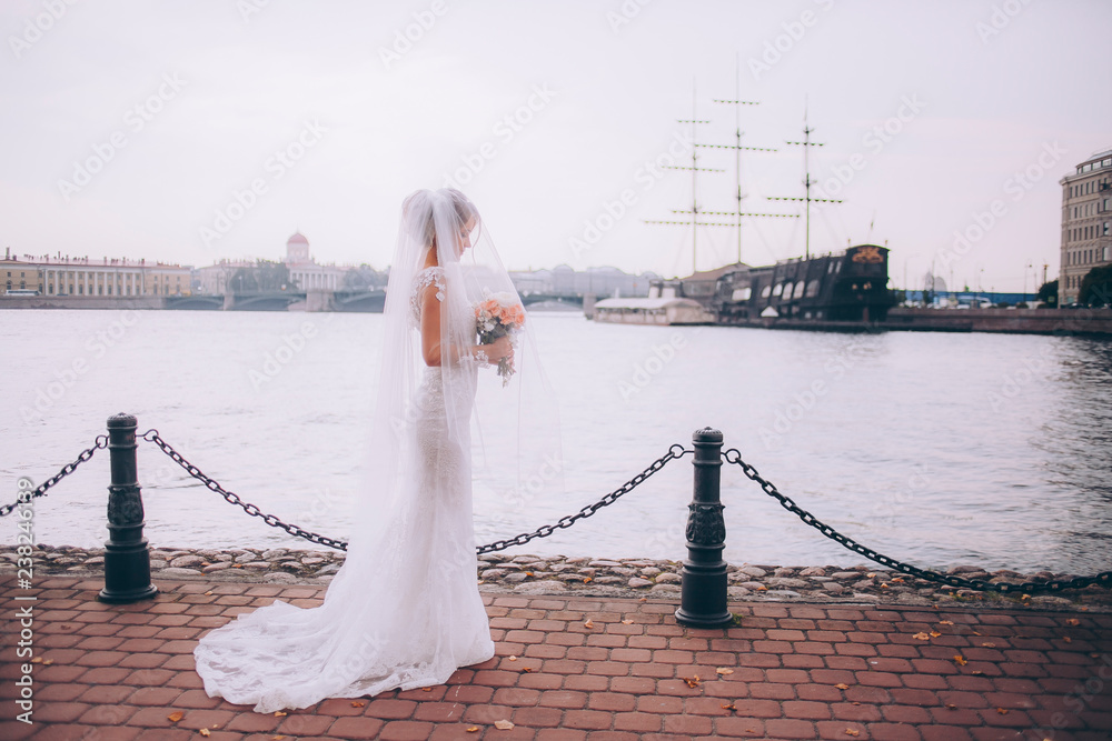 Obraz premium Portrait of a beautiful bride in a white wedding dress and bouquet