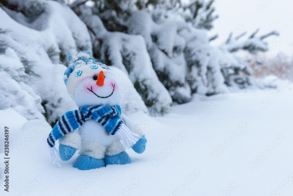 toy cheerful snowman in the winter forest on the background of snow-covered trees