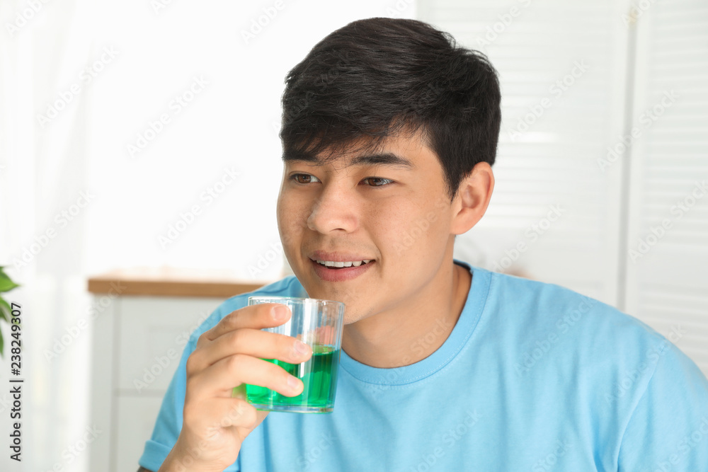 Man holding glass with mouthwash in bathroom. Teeth care Man holding glass with mouthwash in bathroom. Teeth care