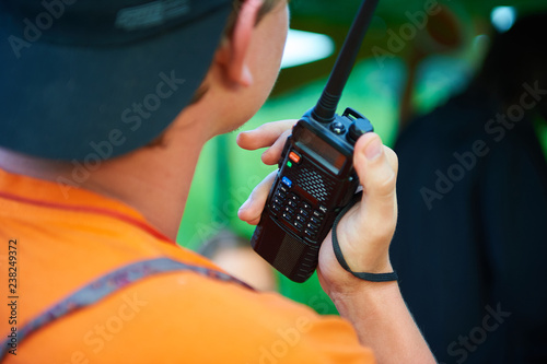 A man with a black portable radio tranciever or walkie-talkie photo