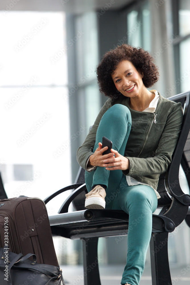 african american woman sitting at station with bags and mobile phone african american woman sitting at station with bags and mobile phone