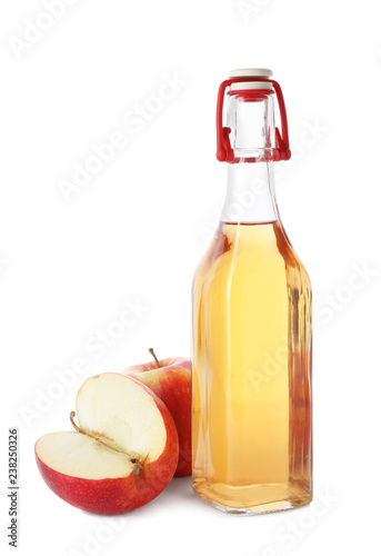 Glass bottle of vinegar and fresh apples on white background