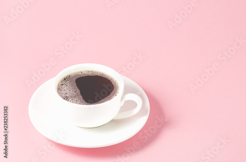white cup with a saucer on a pink background/white cup of espresso with a foam on a pink background, selective focus and copy space