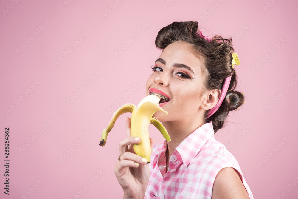 pinup girl with fashion hair. pin up woman with trendy makeup. banana dieting. retro woman eating banana. pretty girl in vintage style, copy space. So tasty