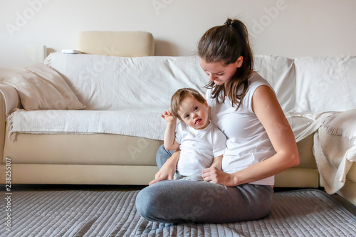 Cute small boy with Down syndrome playing with mother in home