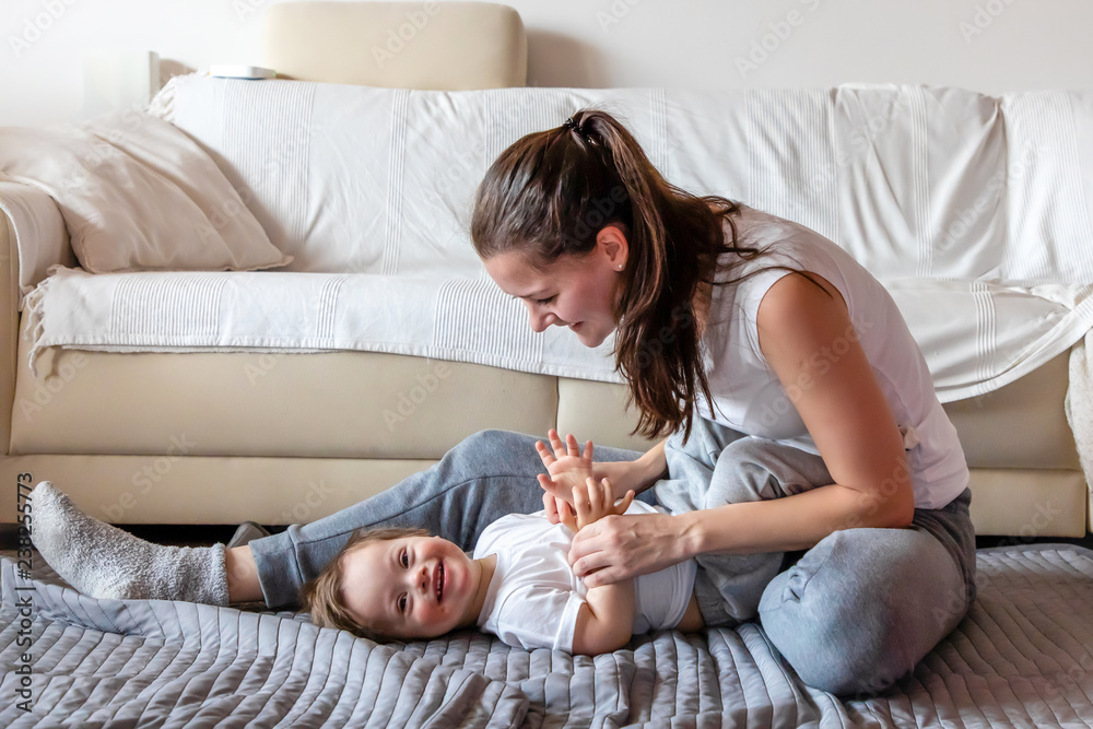 Cute small boy with Down syndrome playing with mother in home Cute small boy with Down syndrome playing with mother in home