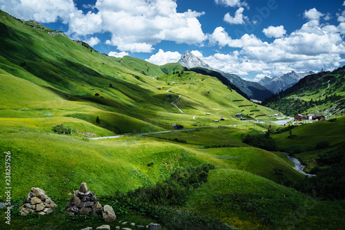 Green alpine meadow in spring with clouds in front of blue sky. Austria, near Lech