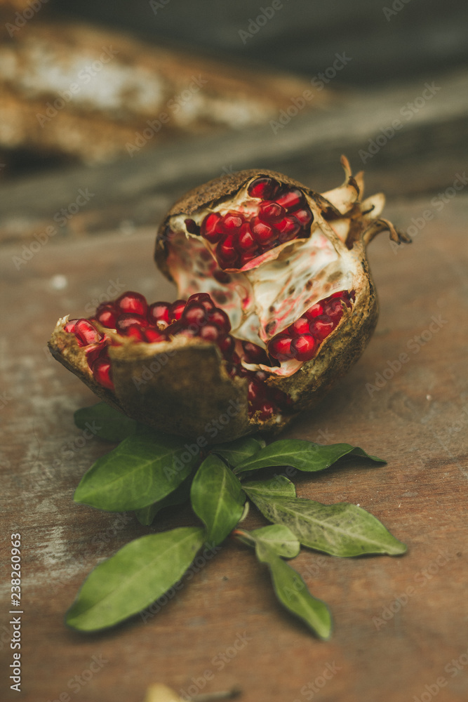 Some red juicy pomegranate, whole and broken, on dark rustic wooden table Some red juicy pomegranate, whole and broken, on dark rustic wooden table