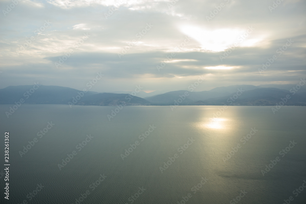soft focus abstract morning foggy time mountain silhouette landscape in calm sea bay water surface with reflection of sun rise light