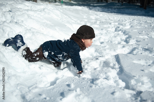 Little boy playing in the snow in winter