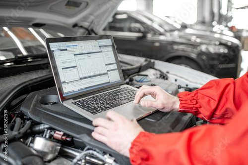 Canvastavla Auto mechanic diagnosing car engine with a laptop with special program, close-up
