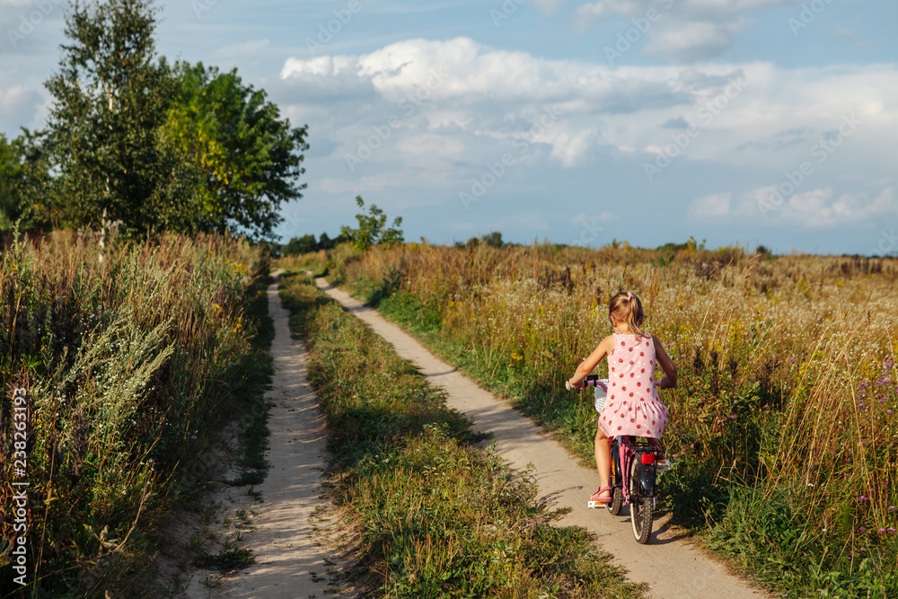 Little girl riding a bike on a rural road