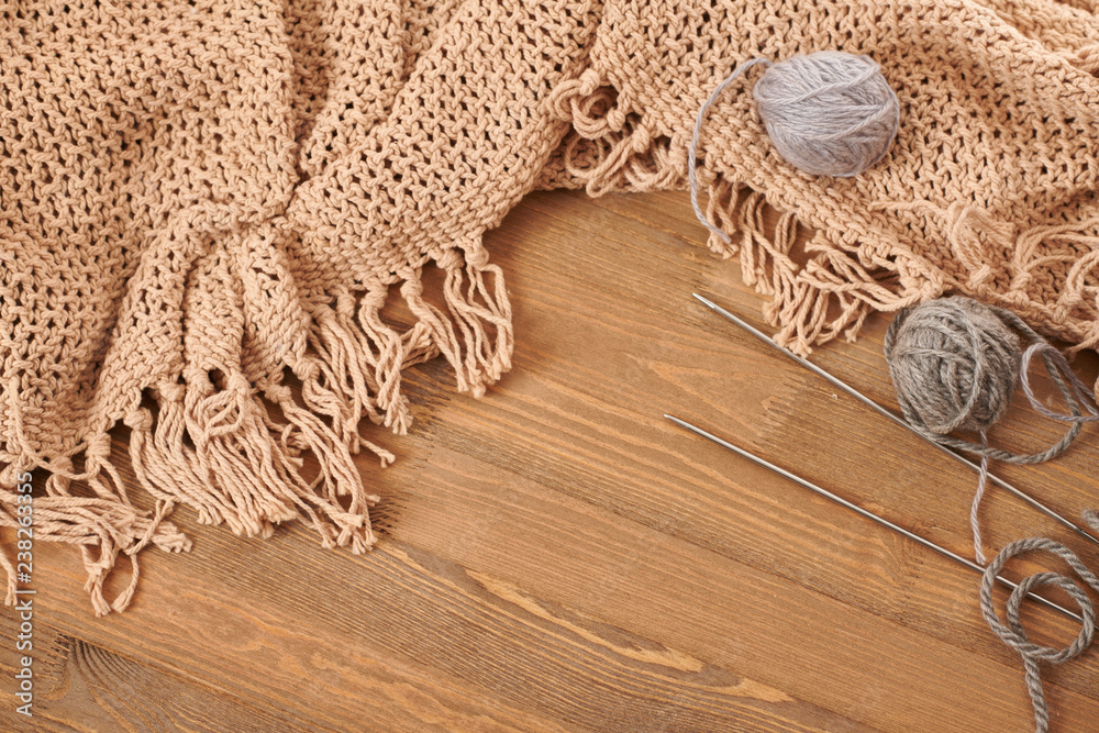 brown knitted plaid and yarn on wooden background brown knitted plaid and yarn on wooden background