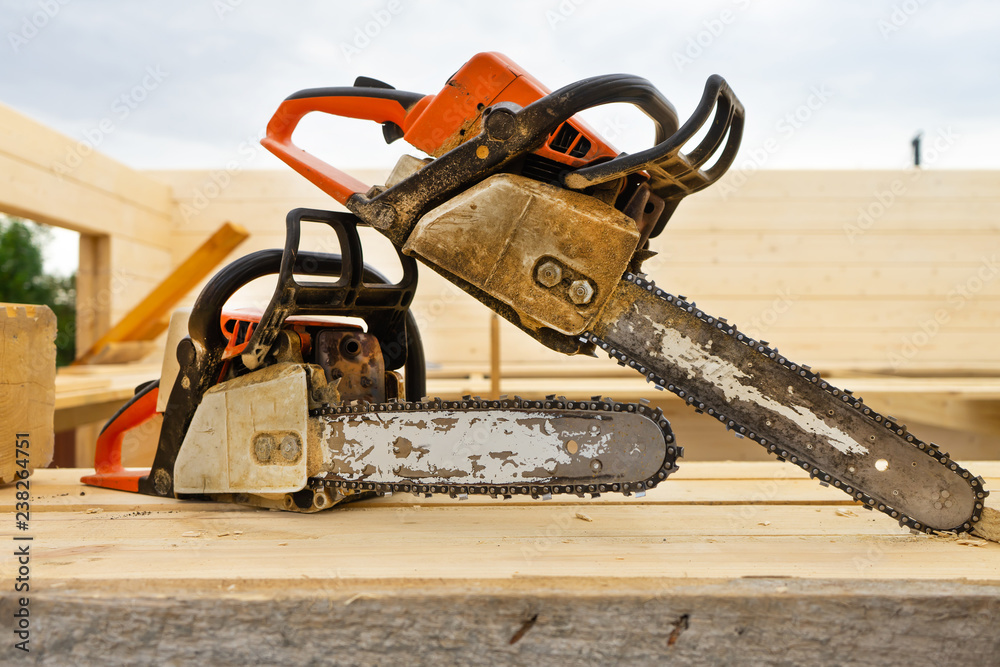 Naklejka premium When construction a wooden house, two chainsaws a bit.