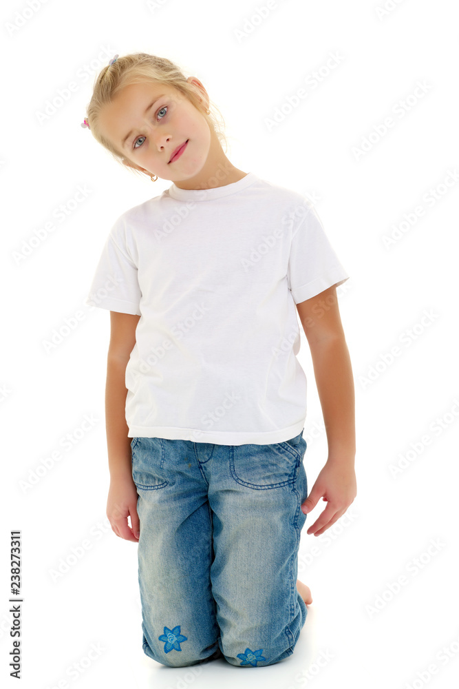 Fototapeta premium A little girl is sitting on the floor in a clean white T-shirt.