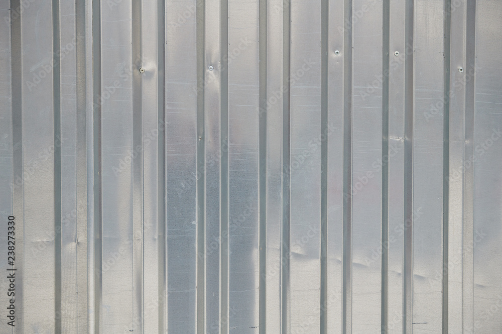The texture of a piece of silver metal sheet with vertical stripes, background