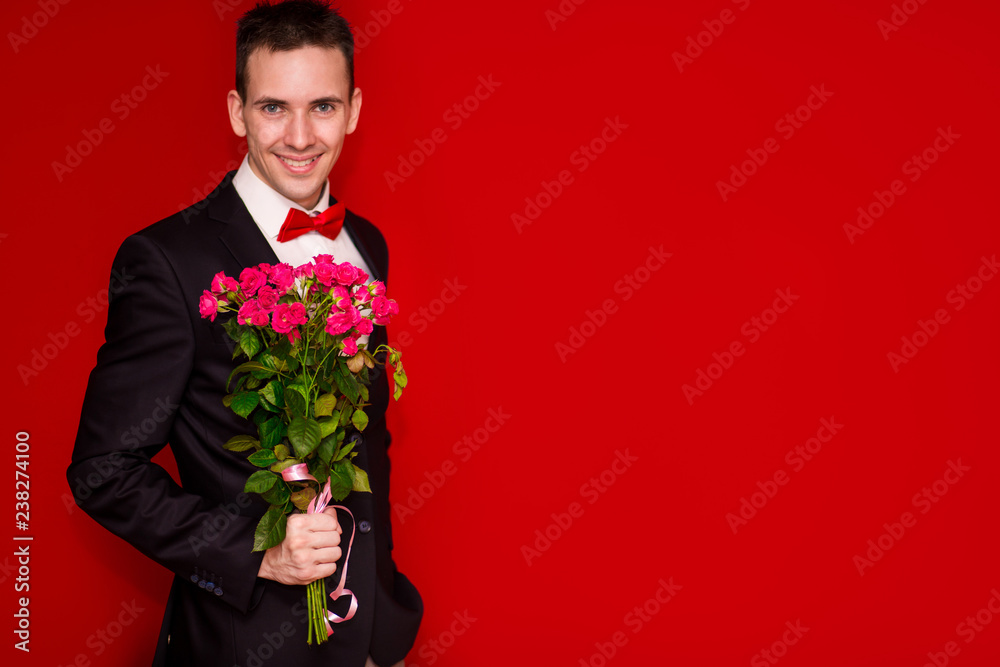 Stylish man in suit holding bouquet flowers isolated on red background Stylish man in suit holding bouquet flowers isolated on red background