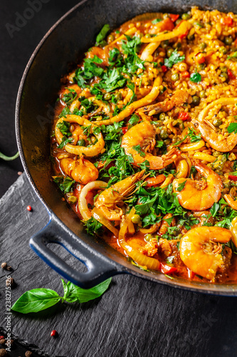 The concept of Spanish cuisine. Paella with seafood, shrimps, squid and greens, cooked in a wok pan on the street. street food.
