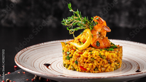 The concept of Spanish cuisine. Paella with seafood, shrimps, squid and greens. Beautiful serving in the restaurant.