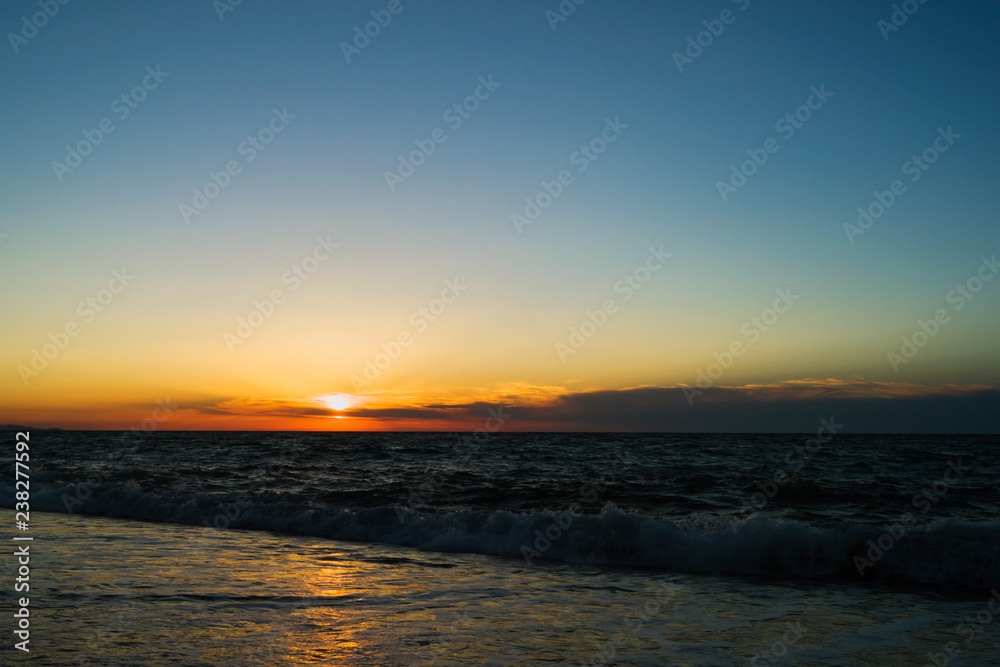 Sunset on the sea. Evening coast of the ocean. Small waves Clouds on the horizon.