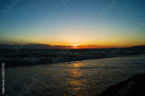 The sun sets over the horizon at sea. Sunset on the ocean. Reflection of sunlight in the water.