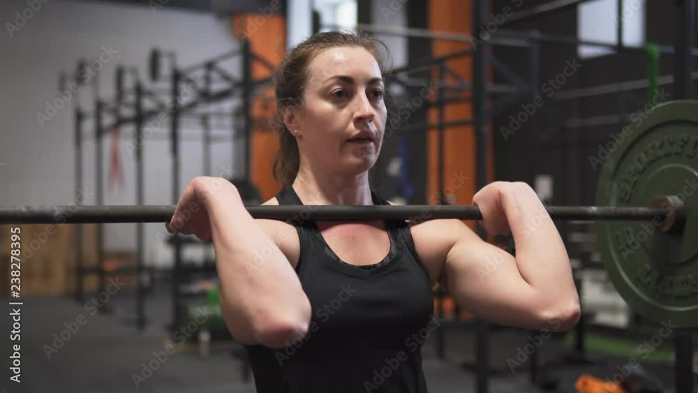 Female doing barbell push press workout in gym Female doing barbell push press workout in gym
