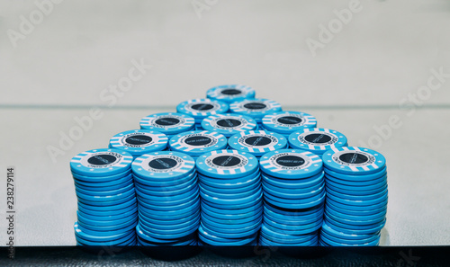 Pyramid consisting of piles of blue poker chips on table with copy space