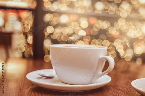 Cup of hot coffee on the wooden table in a coffee shop, blur background with beautiful bokeh effect