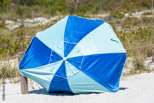 Sanibel Island  USA Bowman s beach  Florida with closeup of umbrella on sand  nobody during sunny day  blown away by hurricane storm wind
