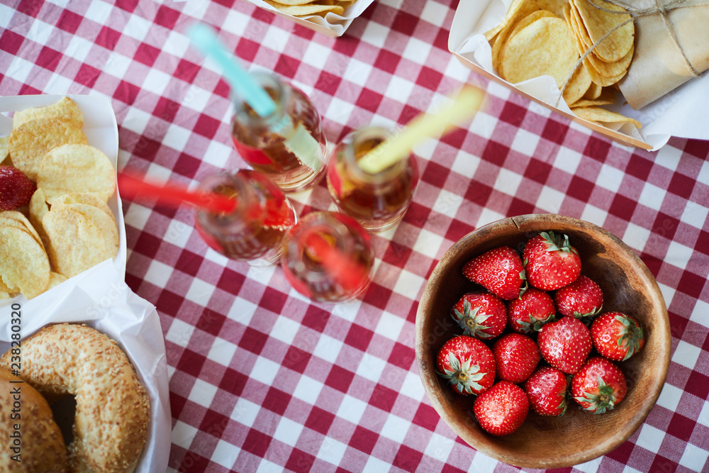 Above view background of rustic table with food set for picnic or summer party, focus on ripe delicious strawberries in wooden bowl and lemonade drinks, copy space Above view background of rustic table with food set for picnic or summer party, focus on ripe delicious strawberries in wooden bowl and lemonade drinks, copy space