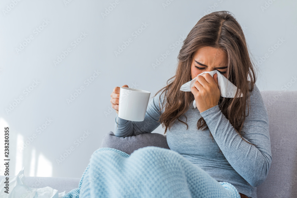 Young woman with cold blowing her runny nose Young woman with cold blowing her runny nose