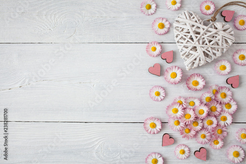 Daisies, petals and hearts on a wooden light background