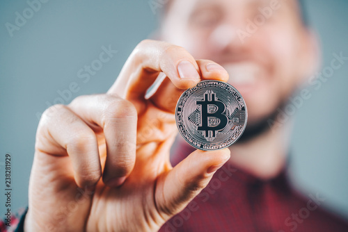 Bitcoin. Close up cropped shot of smiling man holding bitcoin in hand. Business, finance, chrypto currency concept.