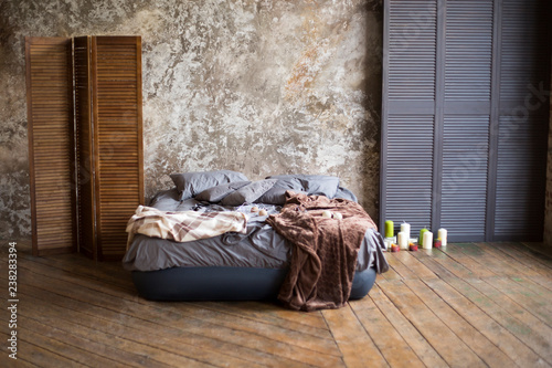 Fotografija loft the room with a gray bed on a wooden floor with gray walls, candles and woo
